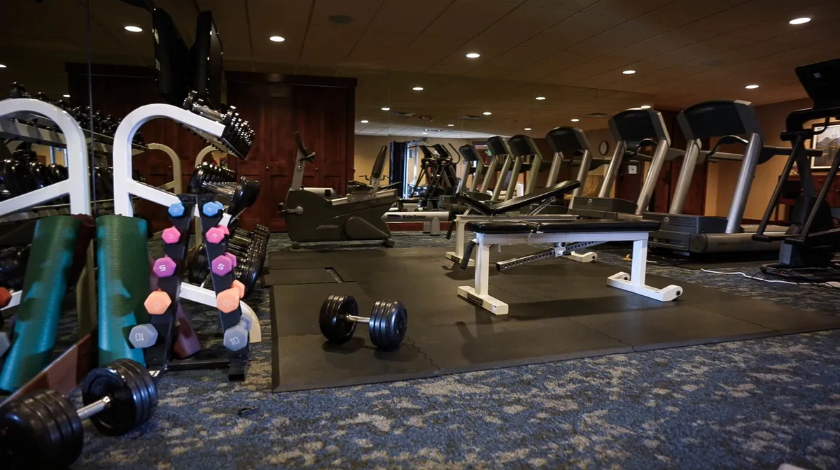 This interior image captures a modern fitness facility equipped with dumbbells, treadmills, and various exercise machines. The space is clean, organized, and well-lit, inviting guests to stay active during their stay.
